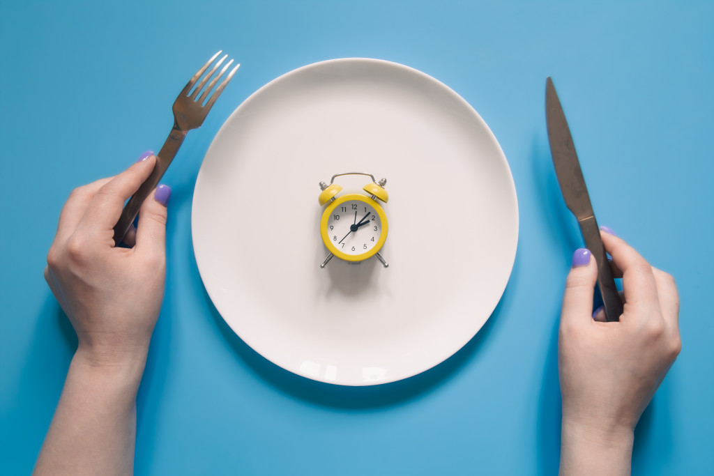 Portion Control Made Easy: How to Eat the Right Amount Without Measuring 43 hands holding knife fork alarm clock plate blue background