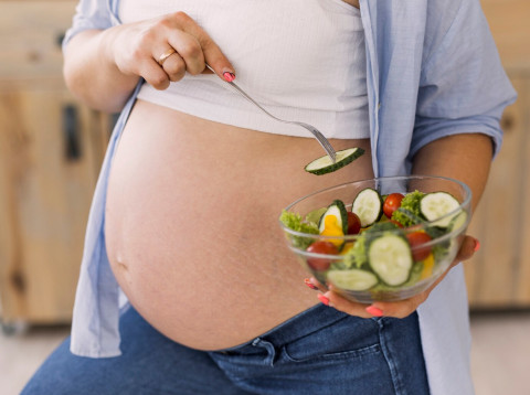 what-to-avoid-during-pregnancy-foods-and-habits-to-skip 46 pregnant woman holding bowl salad 23 2148301955