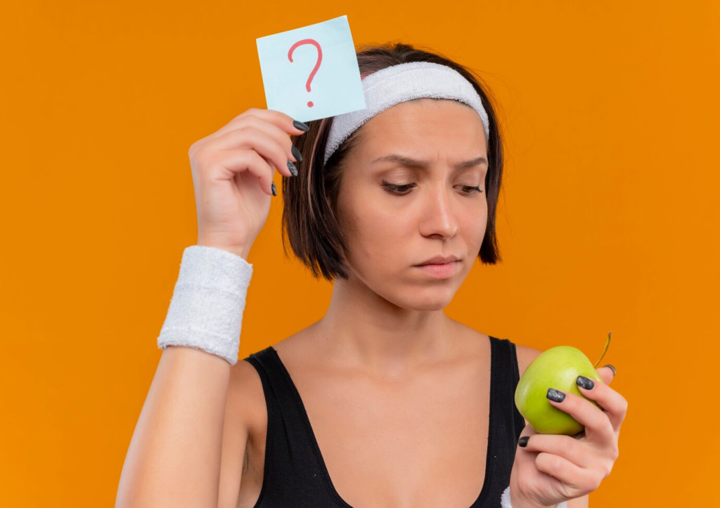 Top Weight Loss Myths Busted: What You Really Need to Know 43 young fitness woman sportswear with headband holding reminder paper with question mark green apple looking apple with pensive expression standing orange wall 141793 49893