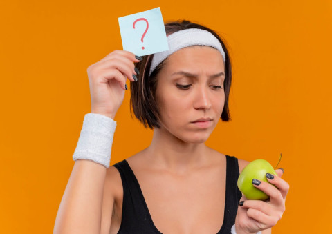 Top Weight Loss Myths Busted: What You Really Need to Know 42 young fitness woman sportswear with headband holding reminder paper with question mark green apple looking apple with pensive expression standing orange wall 141793 49893